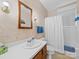 Well-lit bathroom featuring a single sink vanity, map-themed wallpaper, and a shower with white tiling and curtain at 208 Park Ave, Wadesboro, NC 28170