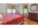 Bright bedroom with hardwood floors, large windows, and a four-poster bed covered with a red floral quilt at 208 Park Ave, Wadesboro, NC 28170