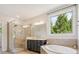Bright bathroom featuring a glass shower, soaking tub, and a dark vanity cabinet with tan backsplash at 2751 Collaroy Rd, Waxhaw, NC 28173