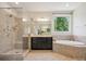 Luxurious bathroom with a glass shower, soaking tub, and modern vanity with dark wood cabinets at 2751 Collaroy Rd, Waxhaw, NC 28173
