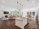 Open concept living space with a kitchen island, dining area, hardwood floors, and a cozy living room with fireplace at 2751 Collaroy Rd, Waxhaw, NC 28173