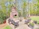 A brick outdoor fireplace area surrounded by mature trees, benches and brick pavers at 3667 Saint Andrews Ln, Gastonia, NC 28056