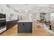 Open concept kitchen with white cabinetry, island with seating, hardwood floors, and stainless appliances at 4412 Foxview Ct, Charlotte, NC 28270