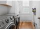 Well-lit laundry room with modern washer, dryer, storage cabinets and hardwood floors at 4412 Foxview Ct, Charlotte, NC 28270