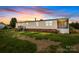 A single-story house with a porch, vinyl siding, brick foundation, with sunset skies at 5110 Old Still Ln, Bessemer City, NC 28016