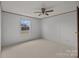Simple carpeted bedroom featuring neutral paint, a ceiling fan and a window looking out to the neighborhood at 5110 Old Still Ln, Bessemer City, NC 28016