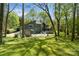Expansive backyard with lush lawn, mature trees, patio, and a charming home at 5416 Woodcreek Dr, Charlotte, NC 28226