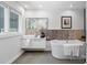 Modern bathroom featuring a soaking tub, double sinks, mosaic tile accents, and large mirror and window at 5416 Woodcreek Dr, Charlotte, NC 28226