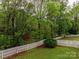 Landscaped backyard with lawn, mature trees, and white picket fence creates a serene space at 6013 Coaching Inn Ct, Charlotte, NC 28270
