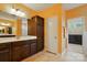 Bright bathroom with double vanity, wood cabinetry, and access to a separate toilet room at 7371 Vanguard Ct, Stanley, NC 28164