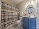 Bathroom featuring blue vanity with updated fixtures, shower/tub combination and patterned floors at 8603 Bookwalter Ct, Charlotte, NC 28277