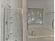 Bright bathroom featuring a shower with glass door and a soaking tub with a window at 9189 Glenashley Dr, Cornelius, NC 28031