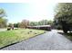 A home's front yard features a gravel driveway, sprawling green lawn, and mature trees offering shade and privacy at 9716 Sunway Dr, Mint Hill, NC 28227