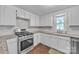 Bright kitchen with stainless steel gas range, granite counters, hardwood floors, and white cabinets at 1975 Old Wilkesboro Rd, Taylorsville, NC 28681