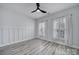 Well-lit bedroom featuring light wood flooring, modern fan, and natural light from two windows at 20202 Dovekie Ln, Indian Land, SC 29707