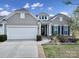 Charming home featuring a two-car garage, manicured landscaping, and a welcoming front porch entrance at 20202 Dovekie Ln, Indian Land, SC 29707