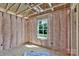 Unfinished bedroom with exposed framing, pink insulation, and a window overlooking the neighborhood at 2628 S Main St, Kannapolis, NC 28027