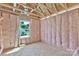 Unfinished bedroom featuring exposed framing, pink insulation, and a window overlooking the neighborhood at 2628 S Main St, Kannapolis, NC 28027