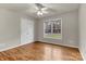 Bright bedroom featuring hardwood floors, a ceiling fan, a double door closet, and a large window with natural light at 4773 Westwinds Rd, Lincolnton, NC 28092