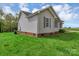 View of the side of a home with gray siding, a brick foundation, and a green lawn at 4773 Westwinds Rd, Lincolnton, NC 28092