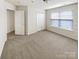 A bright bedroom featuring neutral carpet, a window with blinds, and a spacious closet for ample storage at 6525 Soapstone Dr, Charlotte, NC 28269