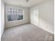A well-lit bedroom with neutral carpet, a window overlooking the backyard, and a closet for storage at 6525 Soapstone Dr, Charlotte, NC 28269