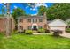 Charming two-story brick home with lush landscaping, a manicured lawn, and a black front door with decorative sidelights at 6744 Wheeler Dr, Charlotte, NC 28211