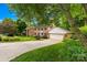 Charming two-story brick home featuring a well-manicured lawn, mature trees, and an attached two car garage at 6744 Wheeler Dr, Charlotte, NC 28211