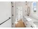 Bright bathroom with wood floors, white cabinets, quartz countertop, and a view of the shower at 7205 Church Rd, Taylorsville, NC 28681