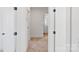 Hallway with carpet, white doors and trim, leading to a bathroom with wood floors and white cabinets at 7205 Church Rd, Taylorsville, NC 28681