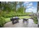 Backyard with a stone patio featuring multiple grills and a lush green lawn surrounded by mature trees at 7518 Porrera St, Charlotte, NC 28214