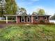 Charming brick home with a covered carport and well-maintained lawn and landscaping at 827 Ford Dr, Lowell, NC 28098