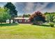 Charming single-story brick home with green shutters, surrounded by mature trees and a spacious, well-kept lawn at 904 Sunbeam Dr, Lincolnton, NC 28092