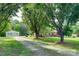Quaint brick home with mature trees and a detached garage, accessible by a gravel driveway and lush green lawn at 904 Sunbeam Dr, Lincolnton, NC 28092