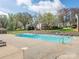 Community pool surrounded by trees and multiple seating areas, ideal for relaxation and recreation at 1022 Kenilworth Nw Ct, Concord, NC 28027