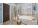 Well-lit bathroom features a glass shower, soaking tub, and neutral tile at 107 Iris Meadow Dr, Mooresville, NC 28115