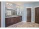 Bathroom featuring double sinks, dark cabinets, a large mirror and light blue walls at 107 Iris Meadow Dr, Mooresville, NC 28115
