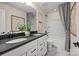 This bathroom includes double sinks with black countertops, white cabinets, and a shower/tub combo with gray curtains at 13709 Roderick Dr # 193, Huntersville, NC 28078