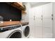 Well-equipped laundry room with modern washer, dryer, built in shelving, and white storage cabinets at 15230 Ravenall Dr, Huntersville, NC 28078