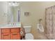 Bright bathroom featuring wood vanity with sink, toilet, and walk-in shower with patterned curtain at 1902 Windmere Dr, Monroe, NC 28110