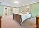 Bedroom featuring green walls, carpet, a queen bed, and two doorways to adjacent rooms at 2313 Beechwood Dr, Waxhaw, NC 28173
