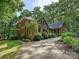 Elegant brick home with attached garage, lush landscaping, and a long driveway through mature trees at 2313 Beechwood Dr, Waxhaw, NC 28173
