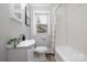 Bathroom featuring tiled tub/shower combo, bright window, and pedestal sink at 2414 Remount Rd, Charlotte, NC 28208