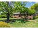 Well-manicured lawn with mature trees framing a charming brick home featuring a brick walkway at 3000 Imperial Dr, Gastonia, NC 28054