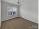 Cozy bedroom with neutral carpet, ceiling fan, and a bright window overlooking the neighborhood at 3114 Parker Green Trl, Charlotte, NC 28269