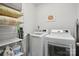 Well-lit laundry room with washer, dryer, shelving, and laundry supplies at 562 Amalfi Dr, Davidson, NC 28036
