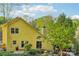 Back exterior view of home featuring yellow siding, a deck, and lush landscaping at 6005 Lanai Ln, Tega Cay, SC 29708