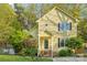 Inviting yellow two-story home featuring a landscaped front yard, trimmed bushes and a picket fence at 6005 Lanai Ln, Tega Cay, SC 29708