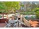 Outdoor stone fireplace and patio area with dining table, seating, and lush backyard landscaping at 6005 Lanai Ln, Tega Cay, SC 29708