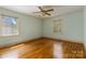 Bright bedroom features hardwood floors, neutral paint, two windows, and ceiling fan at 6921 Thermal Rd, Charlotte, NC 28211